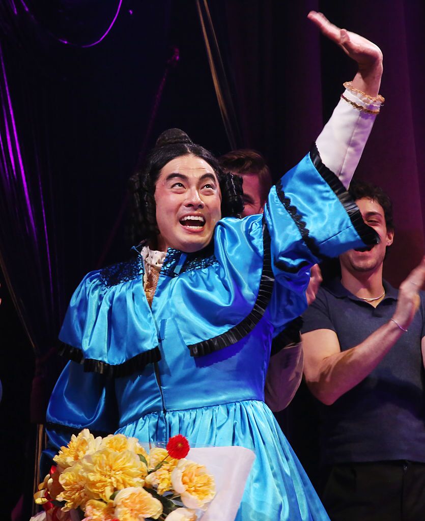 Bowen Yang in a blue Mary Todd Lincoln costume raises a hand during his first Broadway curtain call.