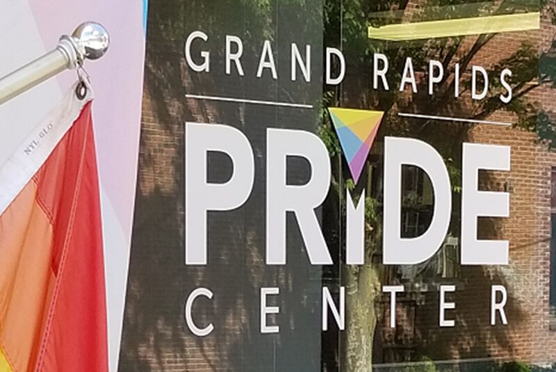 Grand Rapids Pride Center lettering on a window beside a rainbow flag