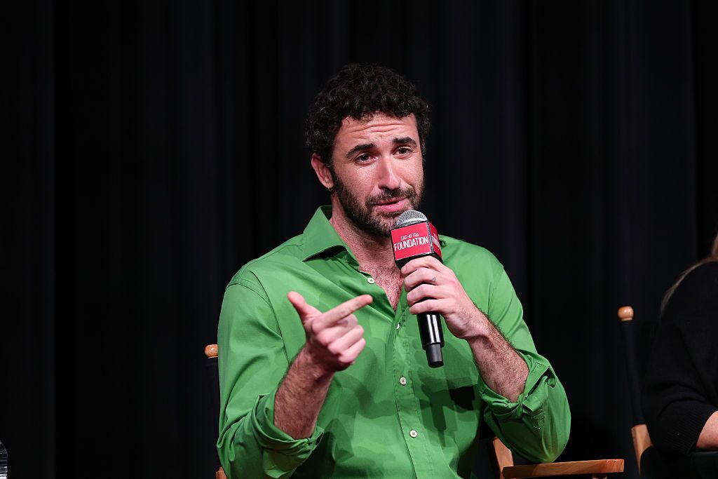 Jordan Firstman in a green shirt speaks into a microphone at a Club Kid discussion.