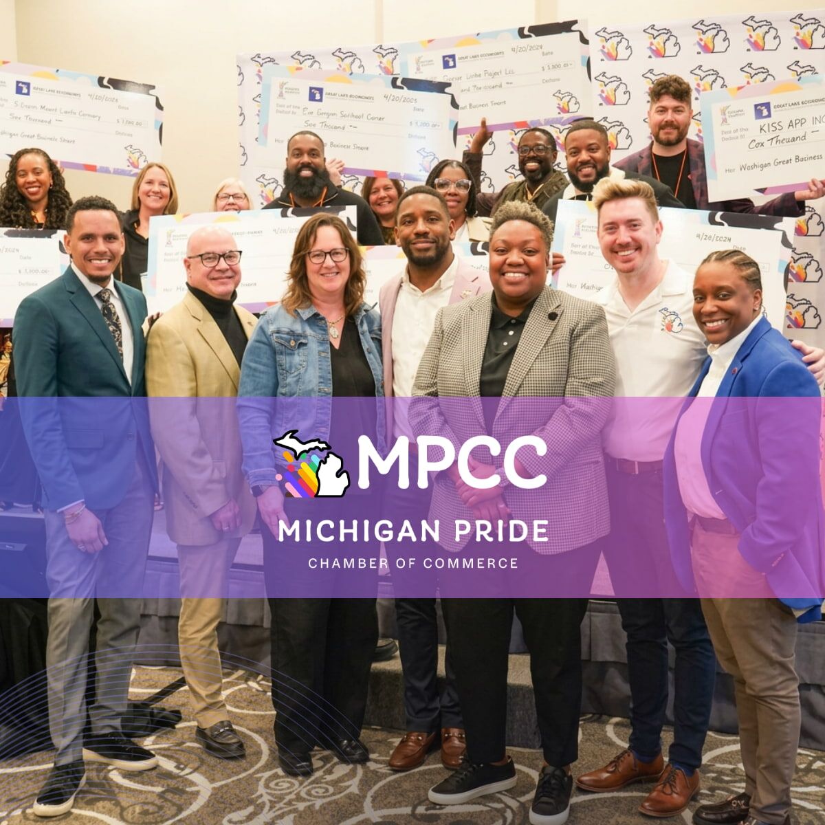 A group poses with ceremonial checks in a Michigan Pride Chamber of Commerce promotional photograph.