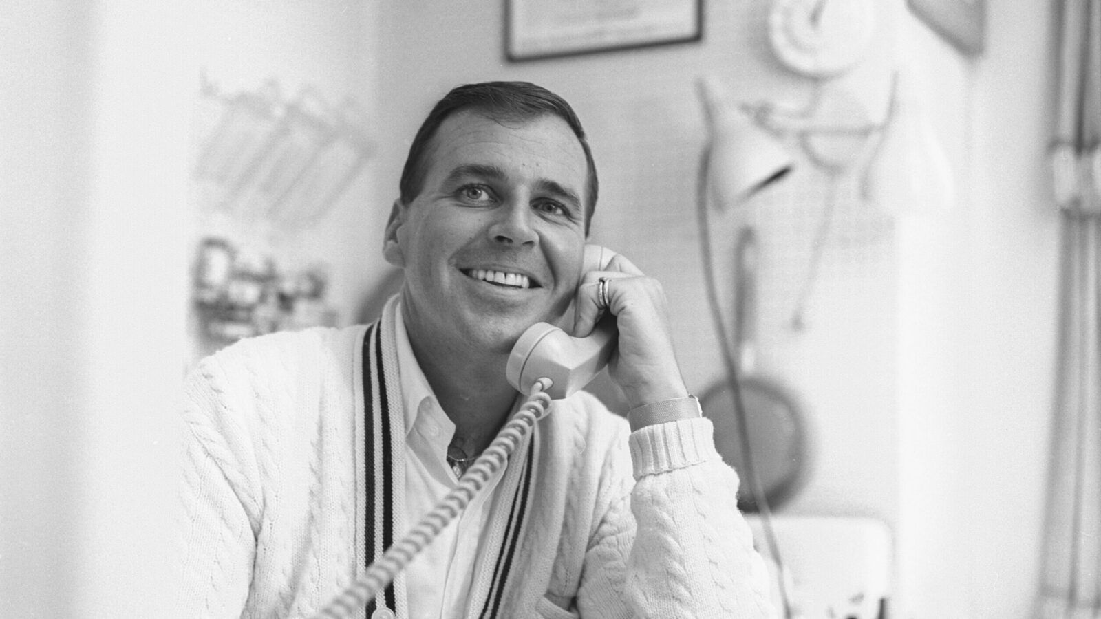 Paul Lynde smiles while holding a telephone in an archival black-and-white portrait.