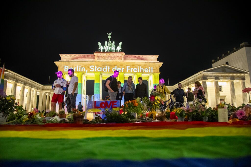 BERLIN, GERMANY - JULY 26: People assemble in front of the Brandenburg Gate, where candles are lit beneath the monument illuminated in rainbow colors and bearing the inscription "Berlin, City of Freedom."on July 26, 2026 in Berlin, Germany. At approximately 10:00pm last night Abdul B. drove the van into a crowd in Tiergarten park, killing one woman and injuring 16. Three victims are reportedly in critical condition. (Photo by Massimo Di Nonno/Getty Images)
